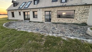 Una casa moderna con facciata in pietra, diverse finestre e vialetto lastricato.