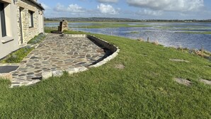 Un sentiero in pietra conduce a un edificio con vista su un lago e dolci colline in lontananza.