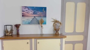 A room with a wooden desk, two cream-colored cabinets, a framed picture, a vase with dried flowers, and a door with a window. - Château privé vacances & séminaires (Méreuil)