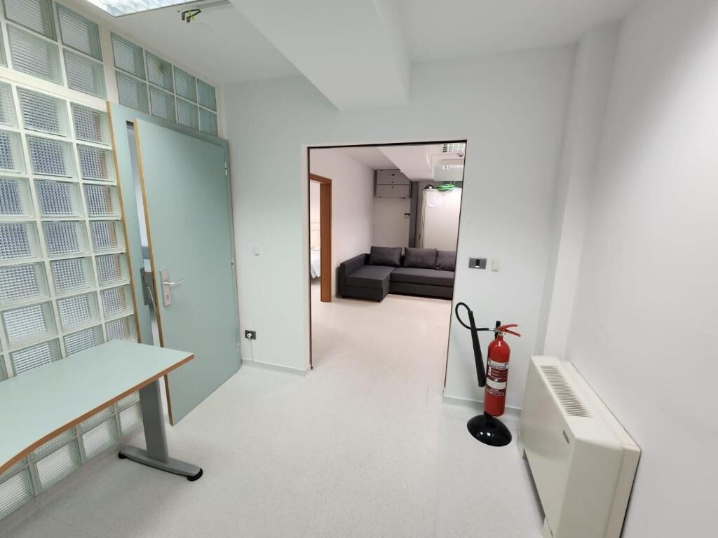 Een kamer met een bureau, een brandblusser en een radiator.