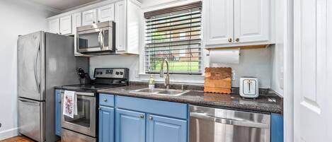 Una cocina moderna con electrodomésticos de acero inoxidable, armarios blancos y una pared de acento azul.