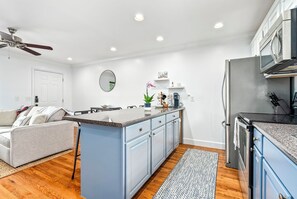 Eine moderne Küche mit einer zentralen Kochinsel, einem Essbereich mit einer Couch und einem Deckenventilator.