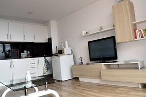 A modern kitchen with white cabinets, a microwave, and a built-in TV. - Sunny Pearl Apartment (Caniço)