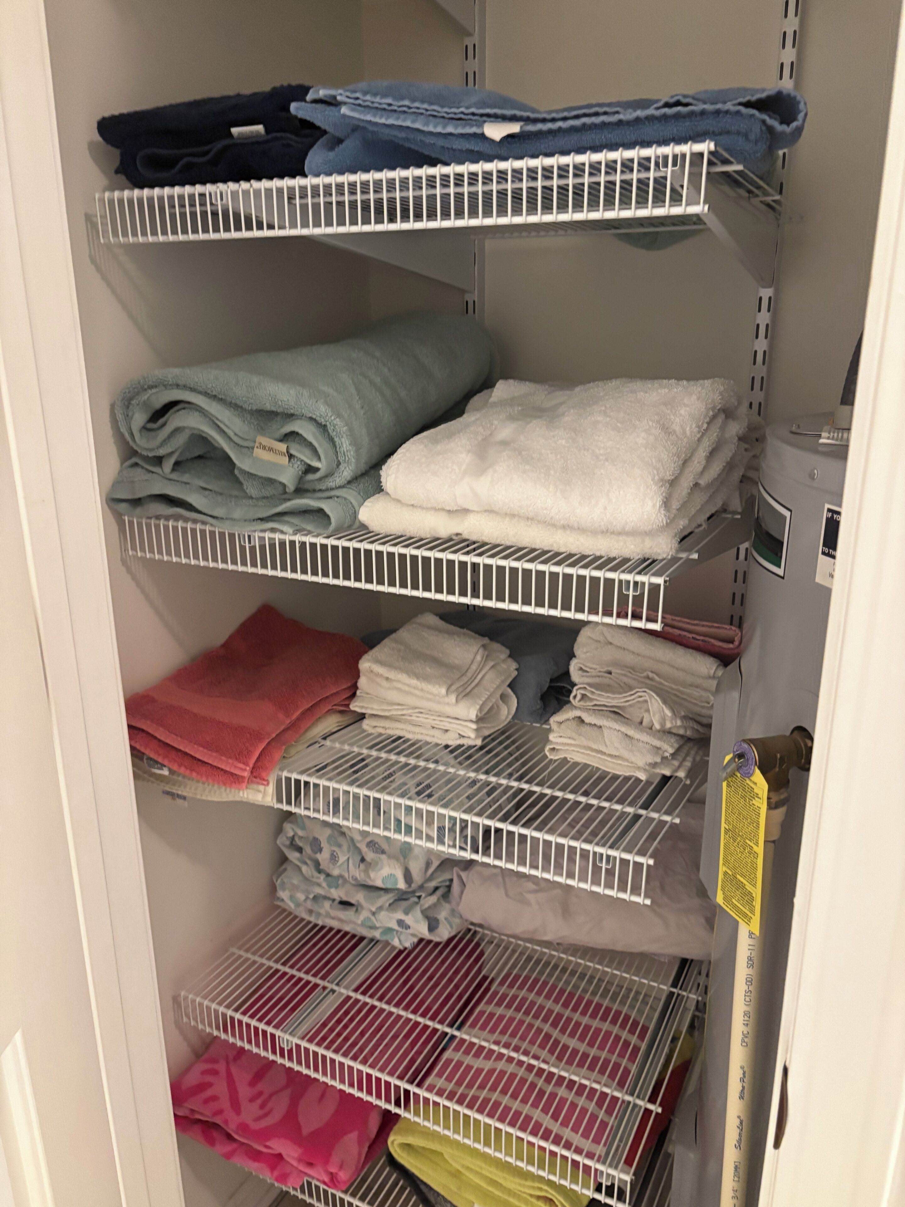 A closet with multiple shelves holding folded towels in various colors.