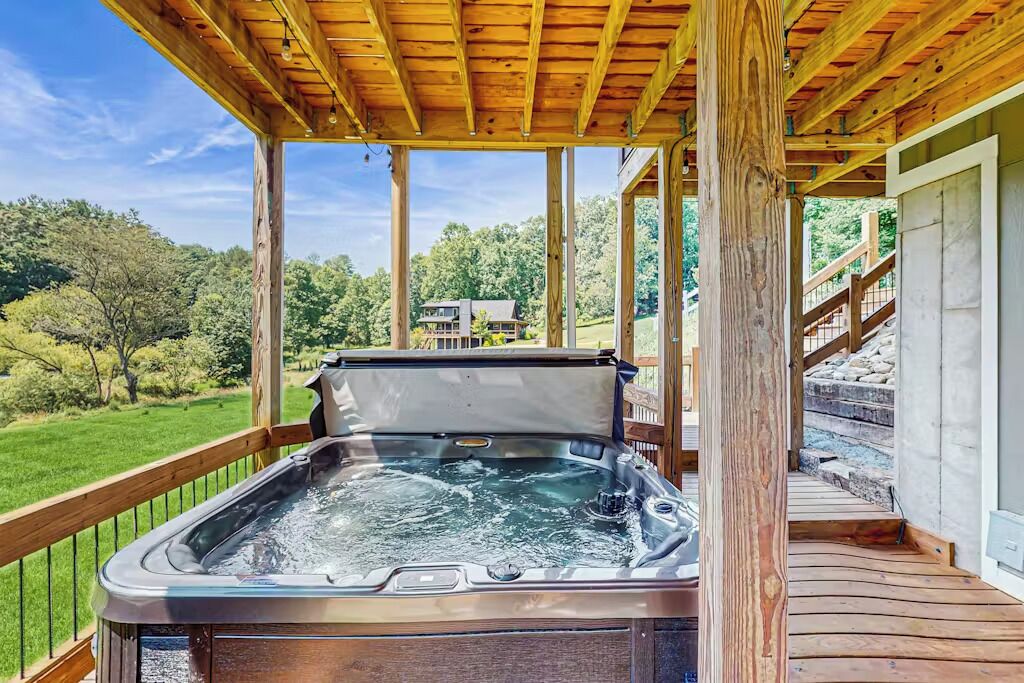 A hot tub under a wooden deck with a view of a house and trees.