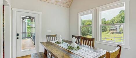 A dining area with a wooden table, chairs, and a view of the outdoors.