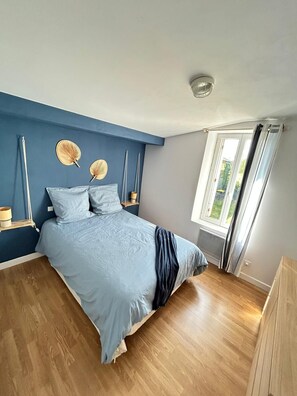 Une chambre Ă coucher avec un lit, des tables de chevet, une fenĂȘtre et une vue sur la verdure.