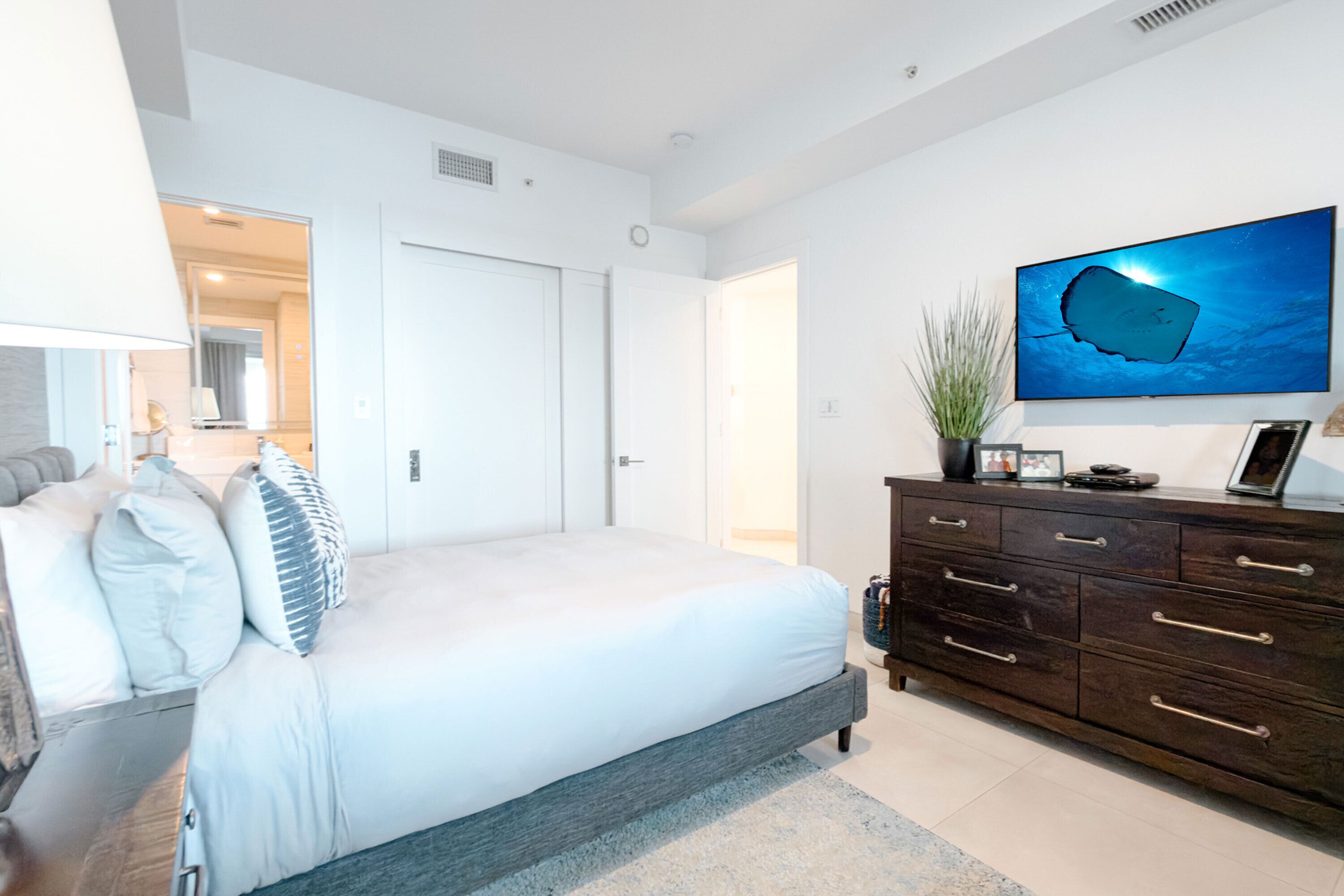 A bedroom with a bed, a dresser, a television, and a wall-mounted artwork.