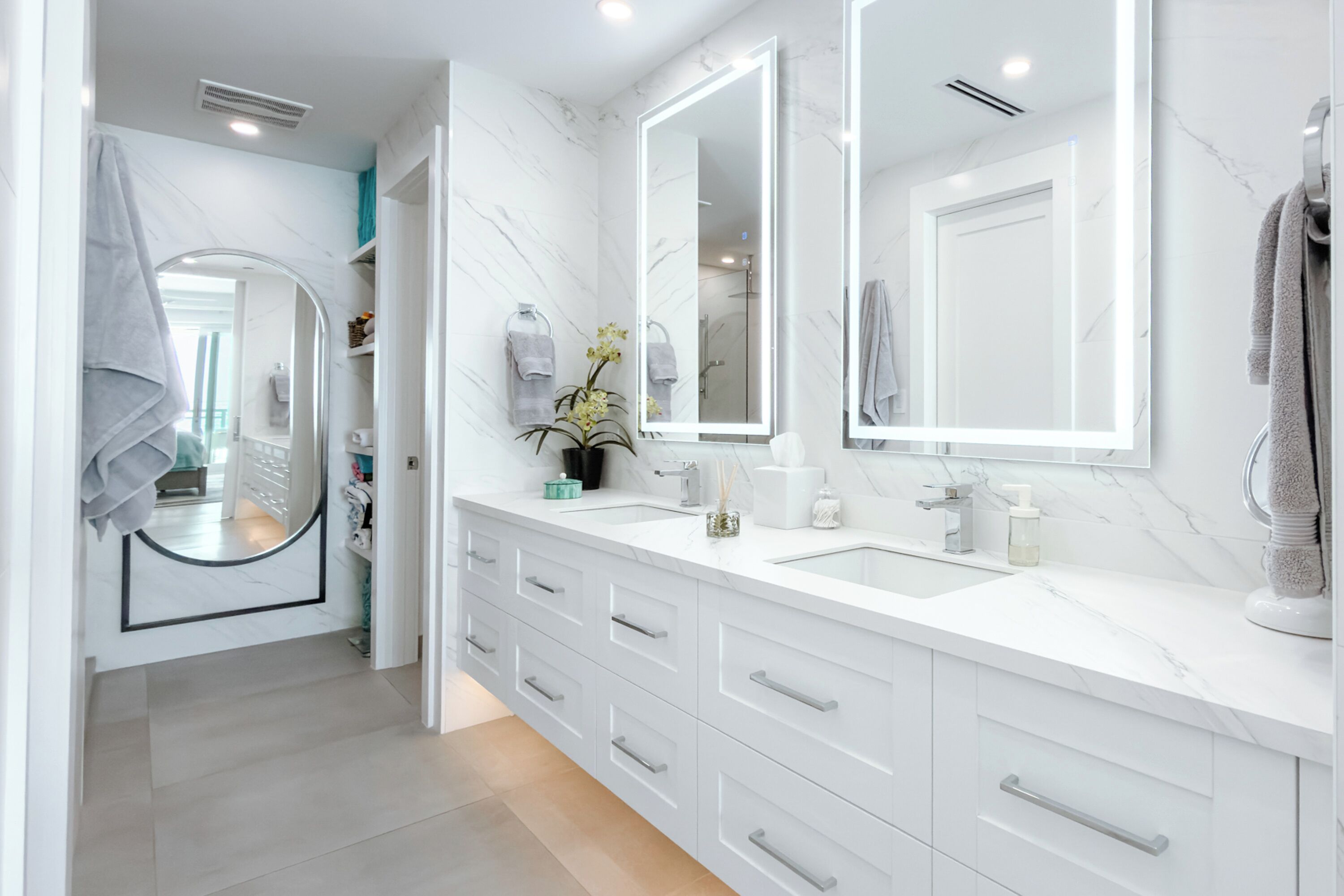 A modern bathroom with white marble countertops, double sinks, and a large mirror.
