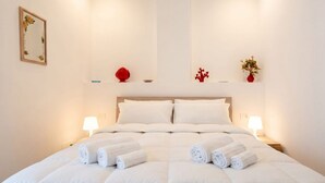 A neatly made bed with rolled towels, a headboard, bedside lamps, and decorative items on the wall. - Lucia Italian Living (Bari)