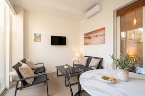 A modern living room with a sofa, chairs, a table, and a TV. - Lucia Italian Living   (Bari)
