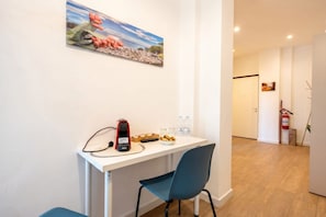 A room with a white desk, a blue chair, a painting on the wall, and a fire extinguisher. - Lucia Italian Living   (Bari)