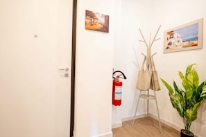 A hallway with a fire extinguisher, a coat rack, and a potted plant. - Lucia Italian Living   (Bari)