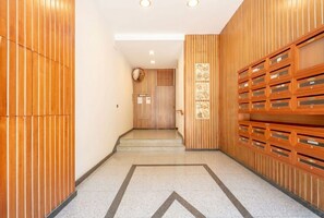 A hallway with wooden paneling, a tiled floor, and a set of lockers on the right. - Lucia Italian Living (Bari)