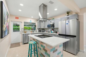 A modern kitchen with stainless steel appliances, a central island, and a view of a pool. - 3bd golf cart, pool, close to beach (Indian Rocks Beach)