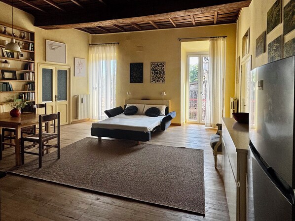 Une chambre à coucher comprenant un lit, un bureau, une bibliothèque et un réfrigérateur.