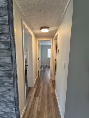 A hallway with wooden flooring, white walls, and a ceiling light. - Lake Life Lodge At Smith Mountain Lake (Moneta)
