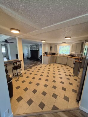 A spacious kitchen with a checkered floor, a dining area with a bar stool, and a fireplace. - Lake Life Lodge At Smith Mountain Lake (Moneta)