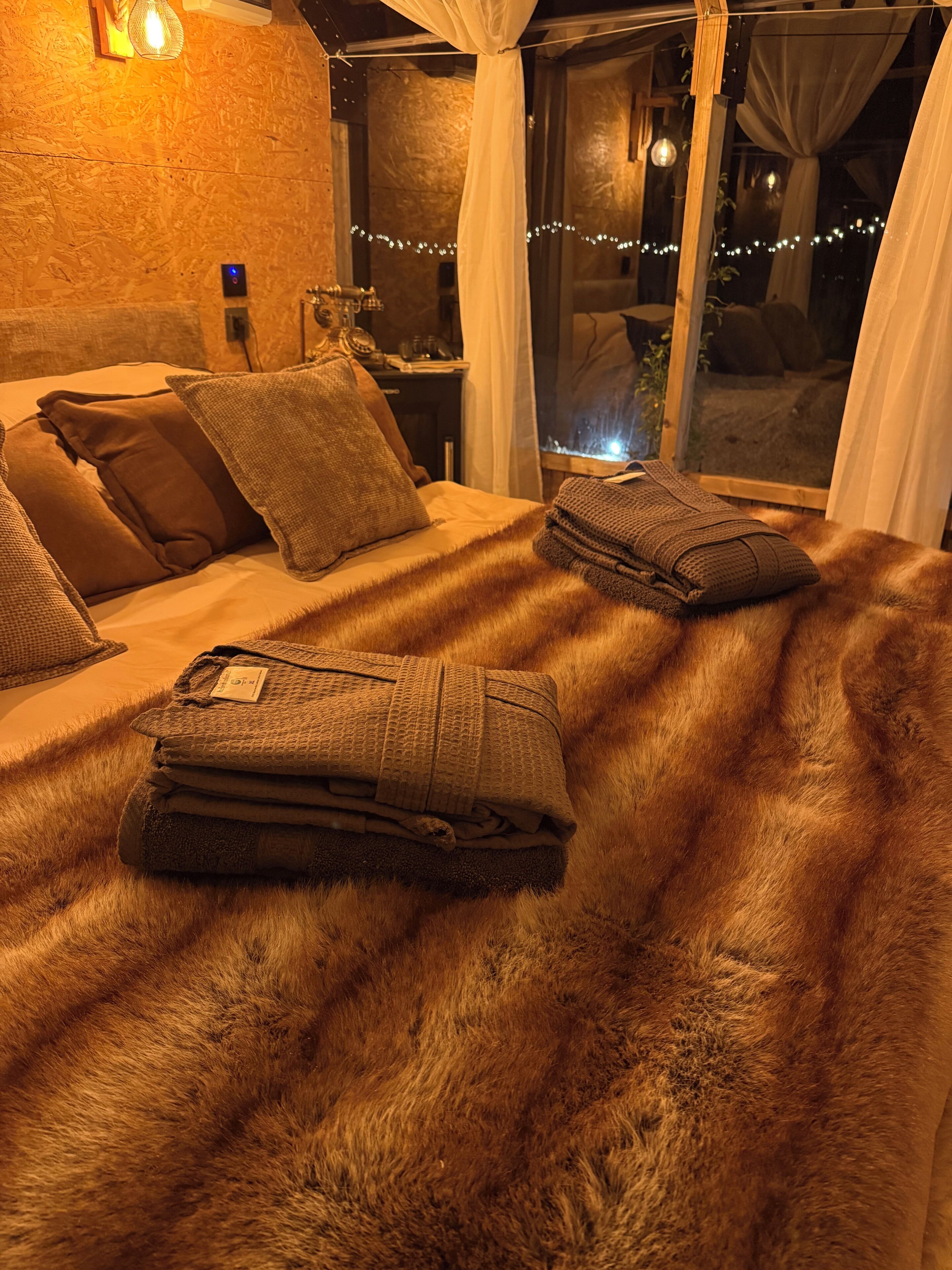 Una cama con cubierta de aspecto aterciopelado, almohadas y mantas dobladas.