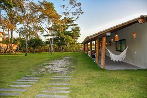 A pathway leading to a building with a covered porch, surrounded by trees and a grassy area. - Mansão Solar Trancoso, 8 minutes from the town center, fully equipped house with pool and spa. (Trancoso)