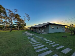 A house with a covered porch, a paved pathway, and a lawn. - Mansão Solar Trancoso, 8 minutes from the town center, fully equipped house with pool and spa. (Trancoso)