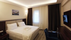 Een hotelkamer met een bed, een bureau, een stoel, een televisie en een schilderij aan de muur.