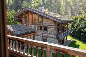 A rustic log cabin with a balcony, surrounded by lush greenery. - Exceptional 12P Chalet With Sauna and Jacuzzi (Megeve)