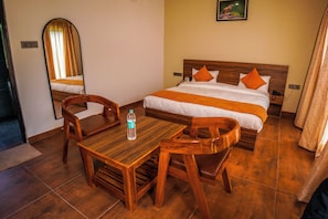 A hotel room with a wooden bed, a wooden table with chairs, a mirror, and a picture on the wall.