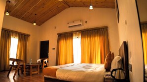 A hotel room with a wooden ceiling, a bed, a desk, and a chair. - Corbett Retreat (Kotabagh)