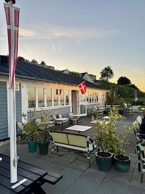 Ravintola, jossa on ulkotila, lippu ja ruukkukasveja.