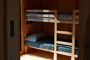 Een houten stapelbed met een kussen en een matras.