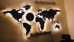 A wall with illuminated world maps and a clock, labeled 'We Plan Your Trip' and 'La-Vista-Tours'. - Lavista Pyramid View (Giza)