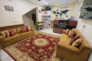 Un área de recepción con dos sofás, un tapete rojo estampado, un mapa mundial en la pared y un banner de La Vista Tours.