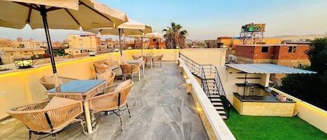 Eine Dachterrasse mit Außenbestuhlung, einer Treppe und Blick auf die Stadt.