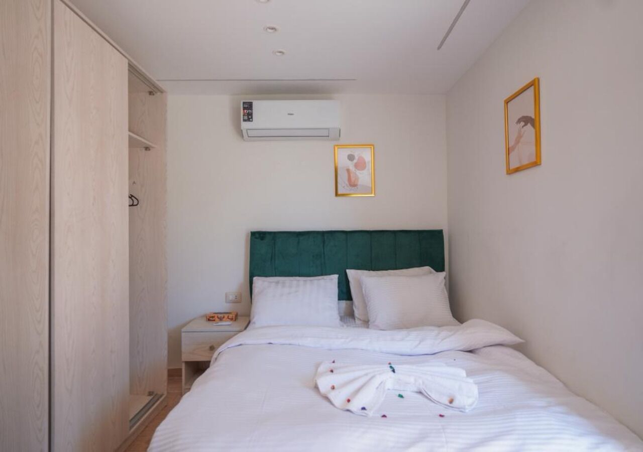Une chambre d’hôtel comprenant un lit, une table de chevet, un appareil de climatisation et une armoire.