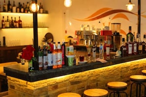 A bar area with a stone counter, stools, and various bottles and glasses. - Lavista Pyramid View (Giza)