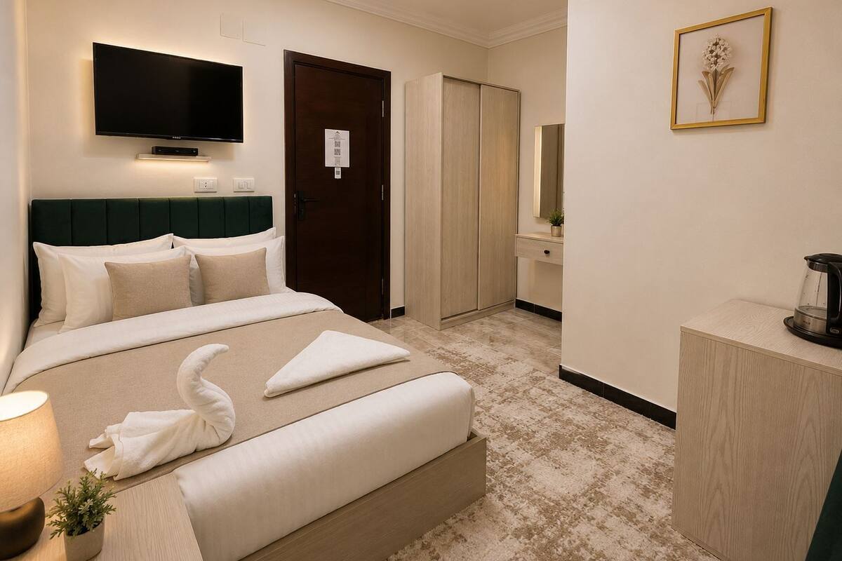 A hotel room with a bed, a TV, a wardrobe, a mirror, and a coffee maker.