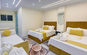 A hotel room with three beds, each with white linens and yellow pillows, and a large mirror on the wall. - Lavista Pyramid View (Giza)