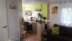 A compact living space with a kitchenette, a sofa, and a dining area. - Air-conditioned mobile home in new condition in campsite with heated swimming pool, quiet plot (La Tremblade)