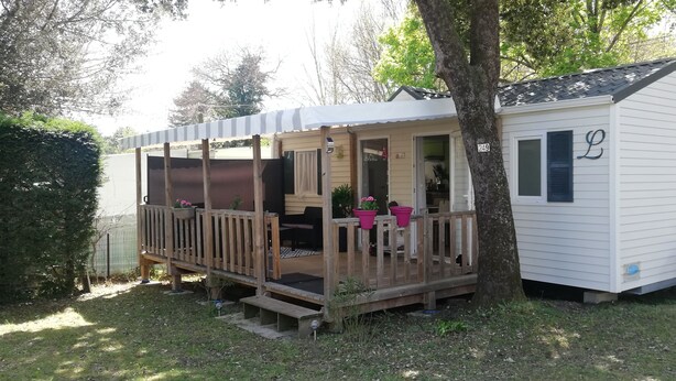 A small, single-story mobile home with a porch, a bicycle, and a number '249' on the side. - Air-conditioned mobile home in new condition in campsite with heated swimming pool, quiet plot (La Tremblade)