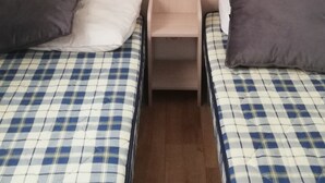 A room with two beds, a nightstand, a small table, and a plush toy on the headboard. - Air-conditioned mobile home in new condition in campsite with heated swimming pool, quiet plot (La Tremblade)