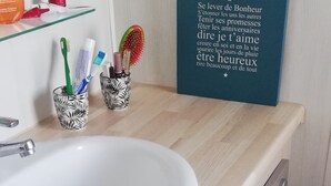 A bathroom with a white sink, two patterned cup holders, a mirror, and a motivational quote on the wall. - Air-conditioned mobile home in new condition in campsite with heated swimming pool, quiet plot (La Tremblade)