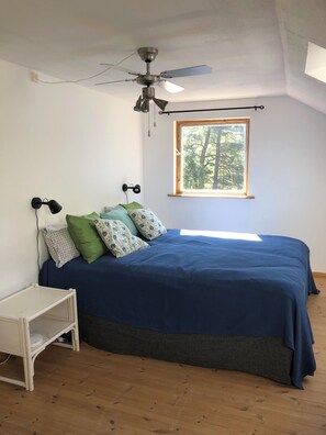 Ein Schlafzimmer mit Bett, Deckenventilator, Fenster und Nachttisch.