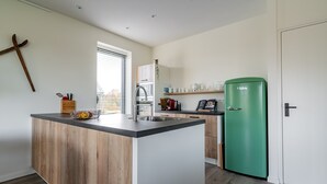Una cocina moderna con una isla de madera, un refrigerador verde y una ventana con persianas.