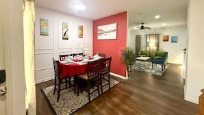 Un coin repas avec une table et des chaises rouges, un tapis à motifs et un mur d’accent rouge.