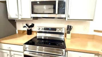 A kitchen with white cabinets, a microwave, an oven, and a countertop with utensils.