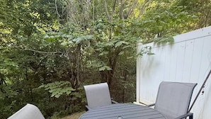 Une table ronde en métal, entourée de quatre chaises, dans un jardin.