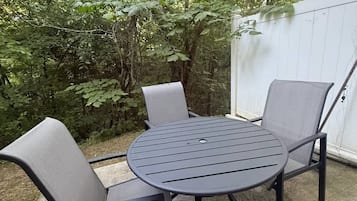 A round metal table with four chairs in a backyard setting.