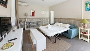 A hotel room with a bed, a sofa, a TV, a desk, and a bathroom. - Apartment with terrace cap d'ail - near Monaco and Beaches (Cap-d`Ail)