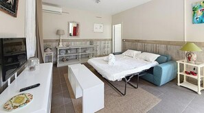 A hotel room with a bed, a sofa, a TV, a desk, and a bathroom. - Apartment with terrace cap d'ail - near Monaco and Beaches (Cap-d`Ail)